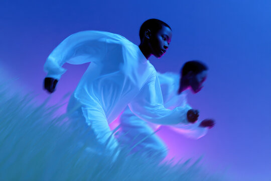 Two models running through grass under blue and pink lights