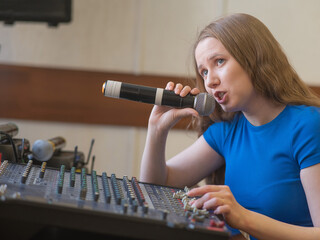 Young woman mixing live sound. Girl recording a song in the studio. 