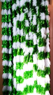 Festive background features hanging green and white decorative fringe, creating a celebratory mood with its vibrant color palette and whimsical arrangement.