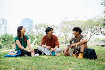 Friends relaxing outdoors in city park, casual students enjoying break. Group of diverse students sitting on the grass, talking and bonding during a study break.