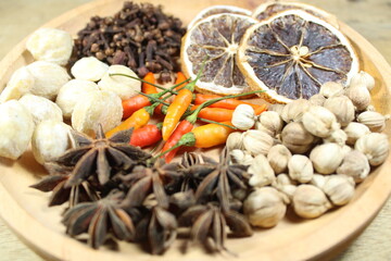 Assorted dried spices and herbs including cardamom, cloves, star anise, dried lemon, candlenut, and...