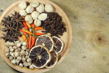 Assorted dried spices and herbs including cardamom, cloves, star anise, dried lemon, candlenut, and...