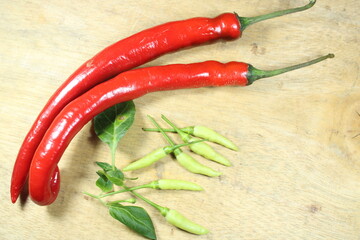 Fresh red and green chili peppers with leaves on a wooden background. Colorful spicy vegetables...