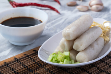 Traditional Indonesian pempek lenjer served with noodles, cucumber slices, and dark vinegar sauce....