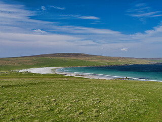 Tranquil Easting Beach on Unst, Shetland, UK, captured with vivid greens and blues under a bright sky, conveying peace and natural beauty.
