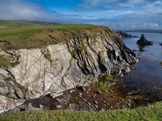 Rugged coastal cliffs meet the azure sea at St Ninian's Isle, Shetland, creating a serene yet dramatic landscape. Coastal cliffs of the Colla Firth Permeation and Injection Belt - Pelite, migmatitic

