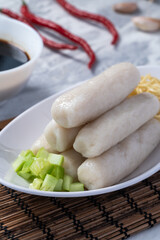 Traditional Indonesian pempek lenjer served with noodles, cucumber slices, and dark vinegar sauce. A savory Palembang specialty on a white plate with garlic and chili garnish