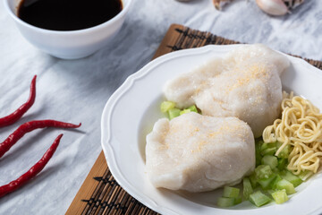 Traditional Indonesian pempek served with diced cucumber, yellow noodles, and spicy vinegar sauce...