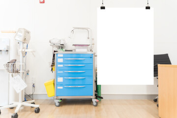 Medical equipment with blank poster in hospital room background, blue emergency cart and clean clinical setting