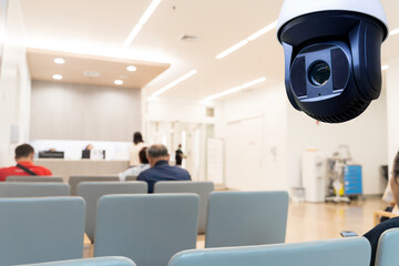 CCTV surveillance camera monitoring waiting area in modern hospital or clinic with people sitting on chairs