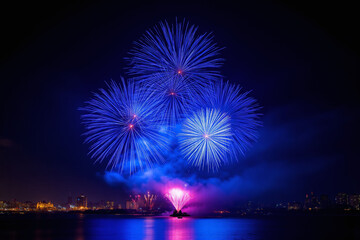 group of blue fireworks in the night sky over a body of water
