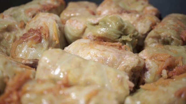 Traditional Ukrainian cabbage rolls, holubtsi, simmering in a frying pan. Stuffed with rice and ground meat, wrapped in cabbage leaves, and cooked in rich tomato sauce. 