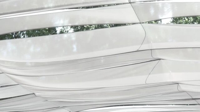 Close-up shot of light fabric waves of a sunshade structure moving gently in the wind. 