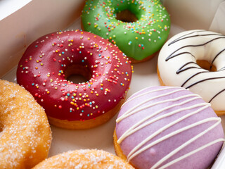 Donuts with different colorful icing designs arranged in a box.