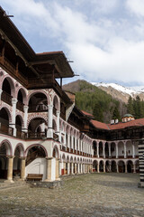 Arched Walkways and Traditional Architecture at Rila Monastery with Snowy Peaks in the Distance