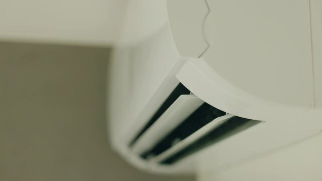 Close-up of a working air conditioner with open airflow flaps blowing cool air in a modern interior.