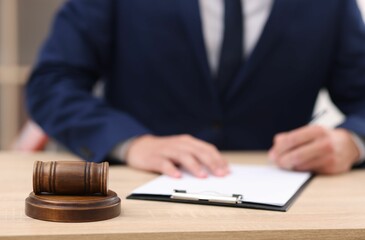 Judge working and gavel on desk indoors, selective focus