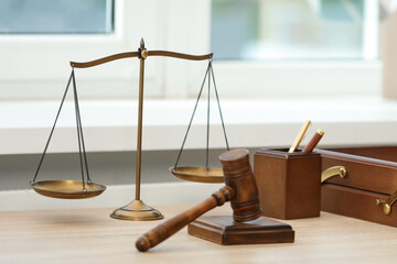 Judge's gavel and scales on wooden table in office
