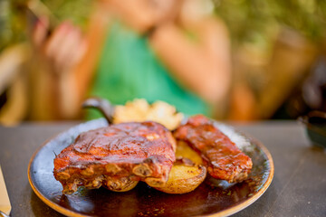 a plate of pork ribs with barbecue sauce and baked potatoes