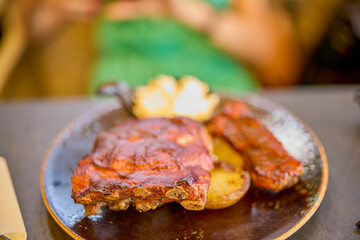 a plate of pork ribs with barbecue sauce and baked potatoes