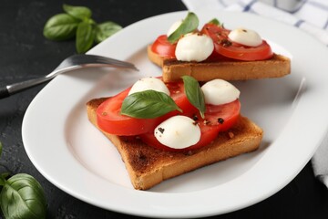 Tasty sandwiches with mozzarella cheese, tomatoes and basil on dark textured table, closeup