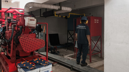 A worker inspects the fire pump system and equipment in a building's utility area.