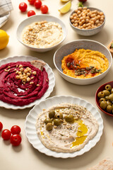  Different types of hummus in bowls and plates. Beetroot, pumpkin, chickpea and bean hummus. 