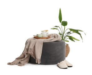 Stylish pouf with tea set, plaid, houseplant and slippers isolated on white