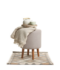 Stylish pouf with tea set, plaid and rug isolated on white