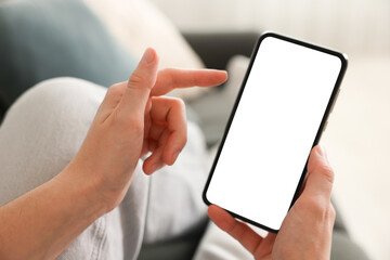 Woman using modern smartphone on sofa at home, closeup
