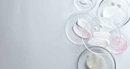 Different cosmetic products in Petri dishes on white background, flat lay. Space for text