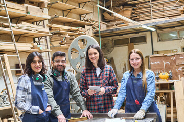 Young apprentices and mentor collaborating in a busy lumberyard workshop