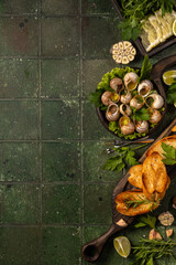 Snails with garlic butter, parsley, and toasted bread on green tiled background