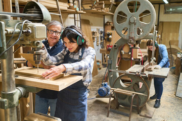 Young apprentice learning woodwork skills in lumberyard workshop
