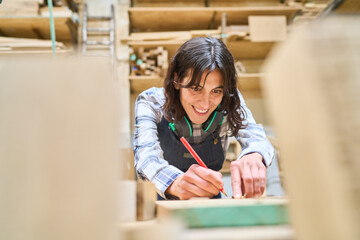 Young woman measuring wood in a busy lumberyard workshop