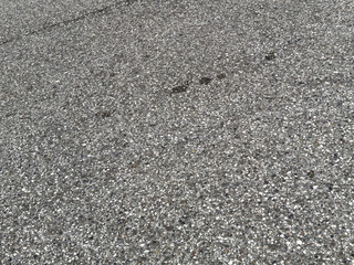 Close-up of gray asphalt pavement with pebble texture