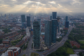 Fototapeta premium Aerial image of Manchester cityscape in the morning with sun-rays breaking through the clouds 