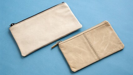 Two Neutral Leather Pouches with Zippers on a Blue Background Flat Lay