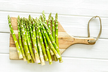 Cooking asparagus. Fresh steams on cutting board on white wooden background top-down