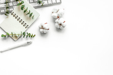 Laptop, cotton branch on white table flat lay copy space. Minimal freelancer home office desk...