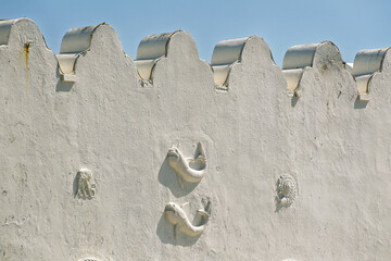 Bas-relief sculpture depicting an anchor with a chain wrapped around its vertical axis, two whales, and small stars on an old building in the port of Mandraki in Rhodes, Greece