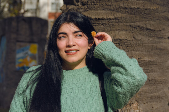 portrait of a beautiful young Venezuelan woman with a flower in her ear outdoors.