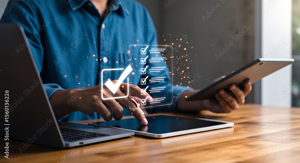Poster person working on laptop and tablet with digital checklist displayed on the screen overlaying device