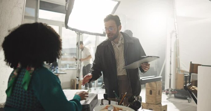 Filming, director and clipboard with man on set for shooting, producer and schedule. Crew supervisor, actor advice and cinematography plan with people for script list, performance guide and media