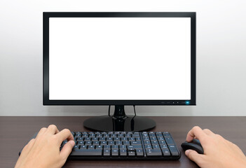 Hands Operating a Computer with a Blank Screen, Keyboard, and Mouse on a Wooden Desk Against a...
