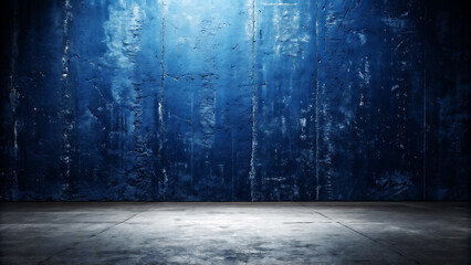 A dimly lit textured dark blue concrete wall with a rough surface illuminated by a bright light from above casting shadows on the floor