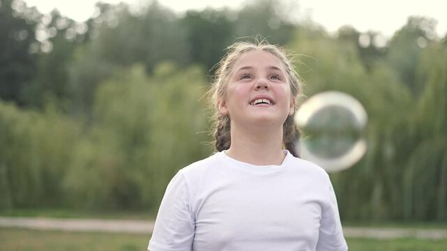 Happy child play with bubble park. Smiling girl enjoys bubble play outdoors. Fun moment as child pops floating bubbles park. bubble play nature park setting. Child engaged in playful bubble activity.
