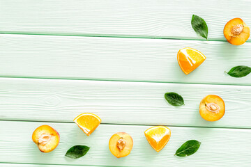 Peach slices and leaves pattern on green wooden background top-down copy space frame