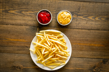 Fast food symbol. French fries on plate on dark wooden table top-down copy space