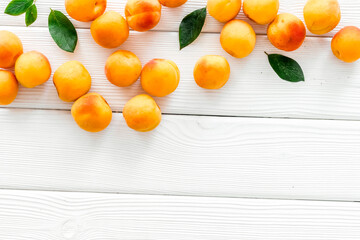 Fruit frame. Apricots and leaves on white wooden background top view copy space